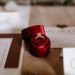 Red box with golden ring placed on table with invitation cards